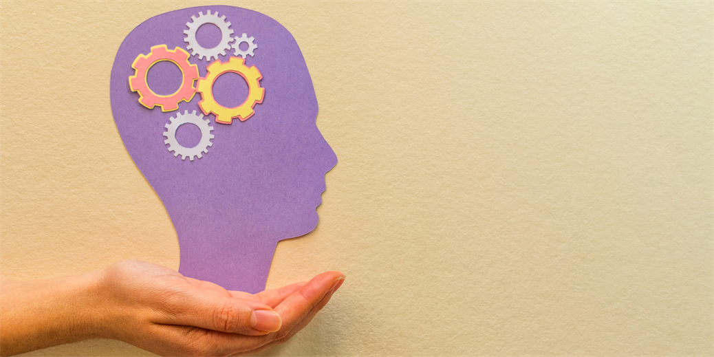 Hand holding purple head silhouette with cogs inside