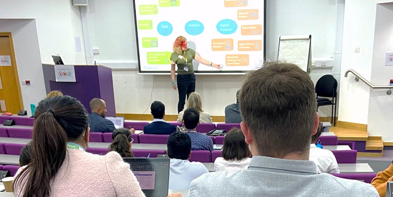 Dr Liz Ford from BSMS presenting in front of a screen to people in a lecture theatre