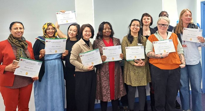 A group of people stood smiling all holding a certificate