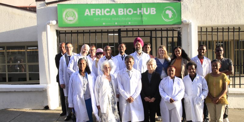 A group of researchers pictured together in front of a green sign reading Africa Bio Hub