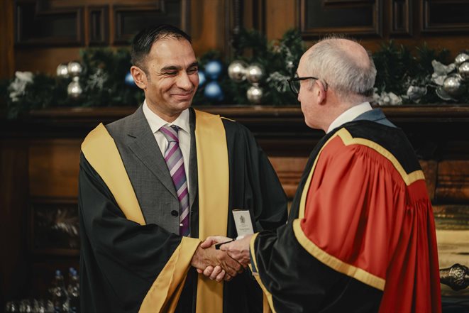 Mahmood Bhutta  shaking hands with someone giving him an award