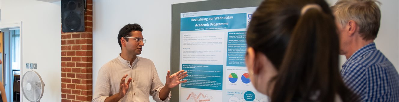 A group of people at an event watching someone present a poster