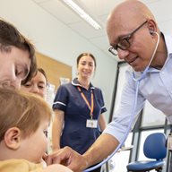 Somnath standing next to a child patient using a stethoscope