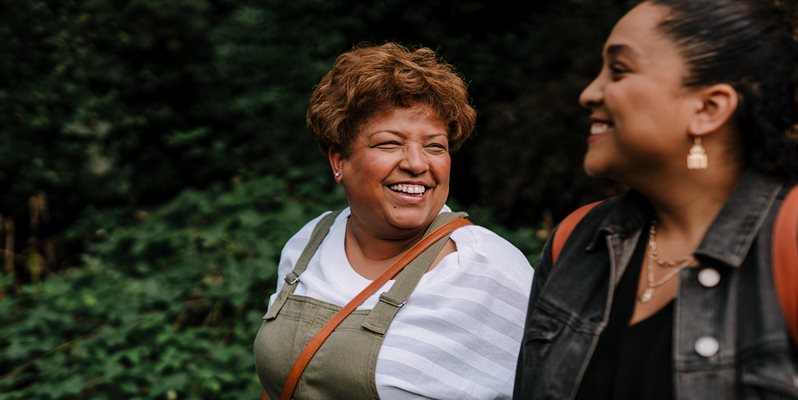 Two woman smiling and laughing on an outdoor walk