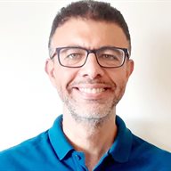 A head and shoulders image of Dr Moustafa Saoud wearing glasses and a blue shirt in front of a white wall