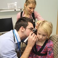 student examines child's ear